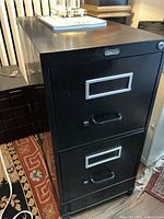 Front view of black two-drawer filing cabinet on wheels