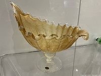 Side view of ruffled gold aventurine Murano glass bowl on pedestal with sticker
