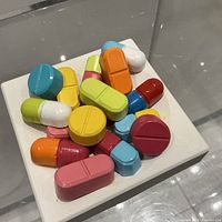 Overhead view of multicolour pill sculpture on white base