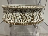 front view of oval ceramic planter showing figural relief and feet