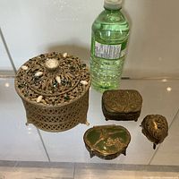 Group shot showing large cylindrical filigree box and three smaller metal boxes for scale