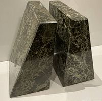 Two trapezoidal dark green marble bookends standing upright