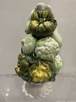Front view of glazed ceramic vegetable topiary showing stacked vegetables and pedestal
