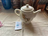 front view of speckled ceramic teapot with floral decal and lid