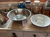 Overall view of stainless steel bowl, enamel basin with cups, galvanized pail