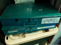 Two stacked teal Fastenal metal storage boxes