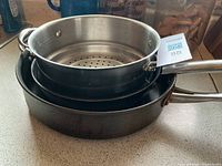 Stacked pans and strainer showing sizes and condition