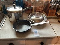 All three pans and two lids on countertop