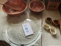 Overview showing large wood bowl with spoon, stack of four small bowls, glass platter, four napkin rings
