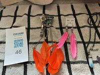 All items laid out: orange feather earrings, silver-tone watch, pink feather earrings, crystal pendant necklace with amethyst charm