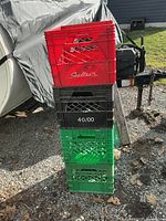 Stack of red, black and green plastic milk crates outdoors