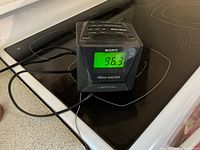 Front three-quarter view of Sony Dream Machine showing display at 96.3 FM, attached power cord, stovetop background