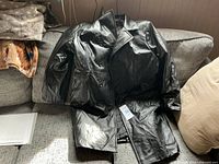 Full view of black double-breasted coat on couch