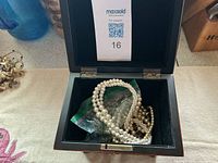 open jewelry box showing faux pearl strands bagged inside