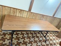 Full view of rectangular laminate folding table against paneled wall