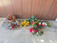 Group of artificial flower stems, greenery, foam bases and wicker basket on garage floor