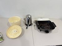 Overview of all three items: salad spinner bowl and basket, stainless steel electric kettle, electric skillet with lid and cord