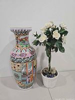 Porcelain vase beside artificial white roses in wicker pot