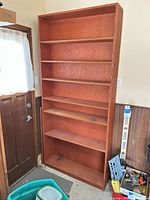 Front view of tall reddish brown plywood bookcase with seven shelves