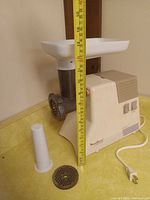Side view of grinder showing height measurement, grinding head, metal plate, plastic pusher, power cord