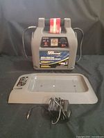 Front view of jump starter showing label, clamps, cradle, charger