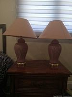 Pair of matching pink ceramic lamps with shades on nightstand