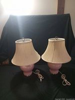 Front view of both pink ceramic lamps with cream shades