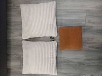 Two white ribbed pillows and one camel pillow on floor