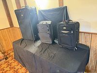 All three black fabric suitcases on table