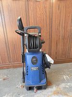 Front view showing Simoniz branding, housing, hose reel, spray gun, detergent tank