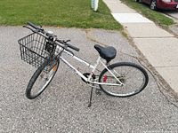 Left side view of white Supercycle Astor bike with front basket showing frame, drivetrain, wheels and accessories