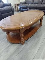 Full view of oval coffee table showing top, legs, and lower shelf