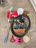 All items laid out: hose reel with hose, buckets, shovel, brush, broom, watering can, hammer, pry bar