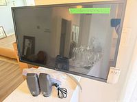Front view of LG monitor on stand with two Logitech speakers and cables