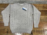 Full view of sweater laid flat with retail hang tag attached