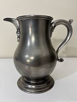 Left profile of pewter pitcher showing handle and foot