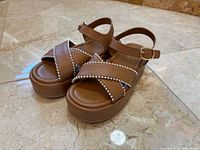 Oblique view of both sandals showing pearl trim, platform height, overall condition