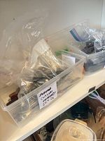 Bin containing mixed stainless steel flatware pieces in plastic bags