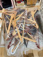 Bagged assortment of natural and dark wooden hangers plus a few white units