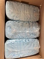 three sealed packs of blue disposable face pads stacked in shipping box