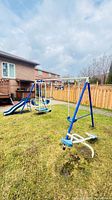 Full view of assembled blue and white metal swing set with slide, swings, glider