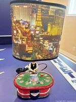 Lamp frontal view showing blackjack table base, dealer figure, Las Vegas skyline shade, attached cord