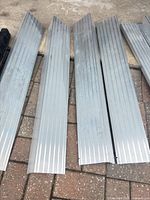 Five long grooved aluminum ramp sections on paver surface