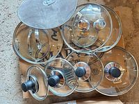 Top view showing all eight glass lids and splatter screen sizes and brands