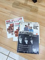 Four Beatles album covers laid out on floor