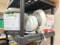 Shelf view showing boxed Mainstay fan, loose Ritetemp heater, and heater box