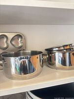 Stockpot, lids, heart muffin pan and additional cookware pieces on shelf
