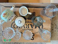 Top view of all items on box showing teapot, mug, lid, jug, tumbler, three glass dishes