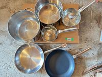 Top view of all pots, pans and lid arranged together showing interiors and handles