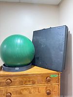 Exercise ball on base beside folded mat on dresser